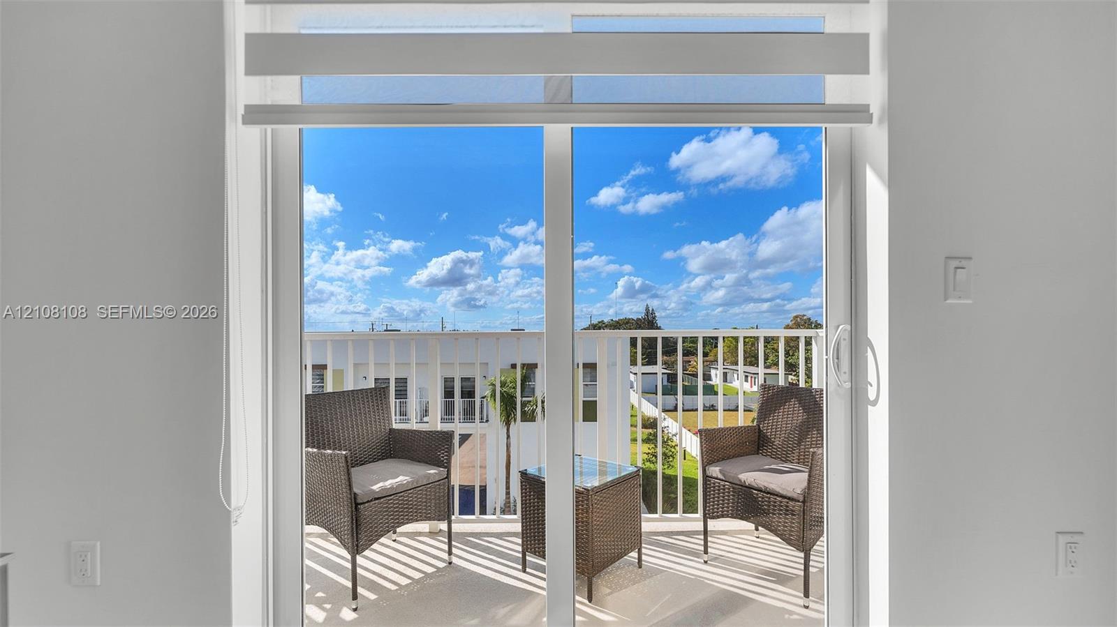 Sliding glass door with integrated roller shade, featuring a white frame and access to a balcony with vertical metal railing Sliding glass door with integrated roller shade, featuring a white frame and access to a balcony with vertical metal railing
