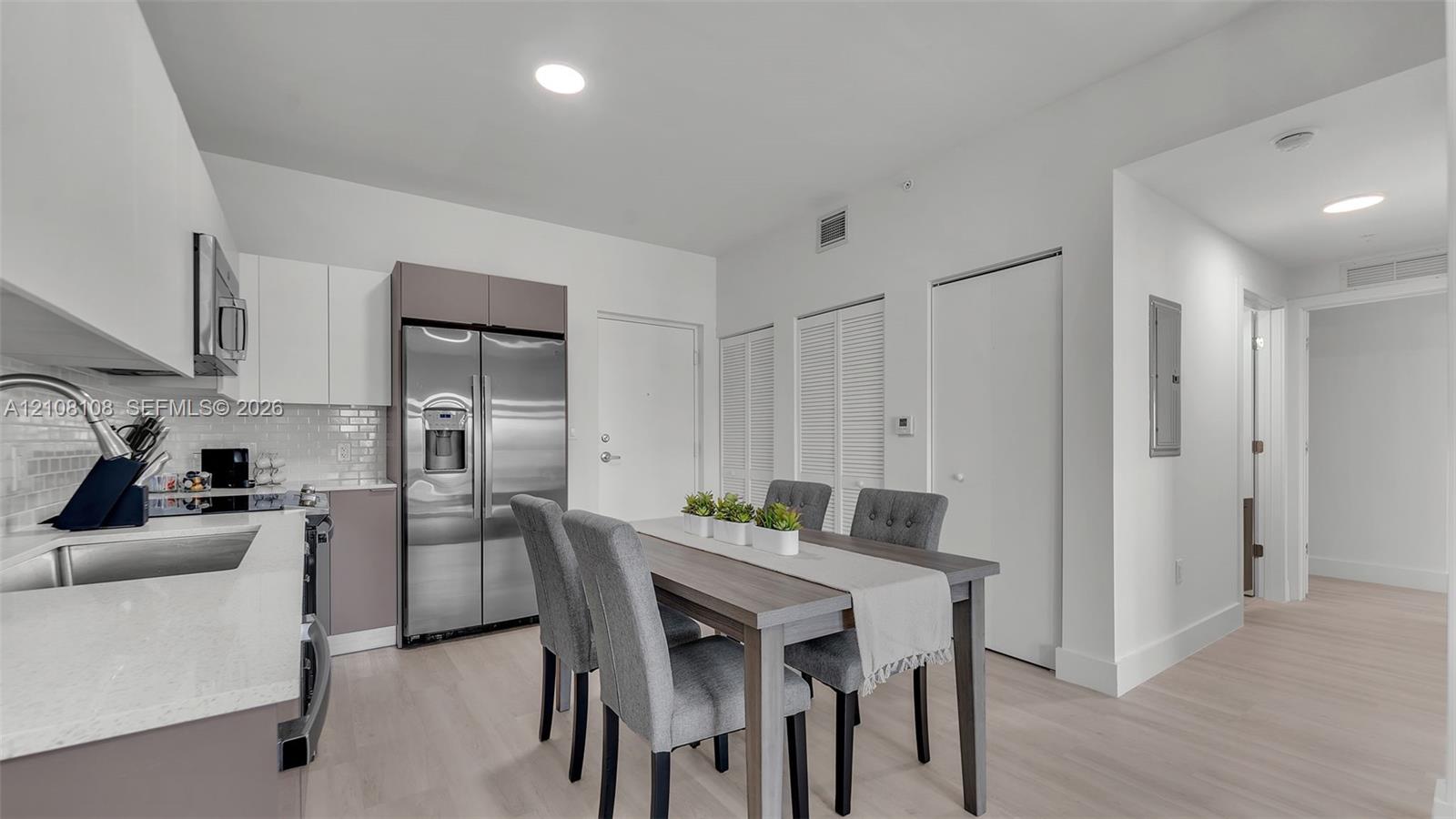 Kitchen featuring stainless steel appliances, white cabinetry, a subway tile backsplash, light-toned wood-finish flooring, and recessed lighting Kitchen featuring stainless steel appliances, white cabinetry, a subway tile backsplash, light-toned wood-finish flooring, and recessed lighting