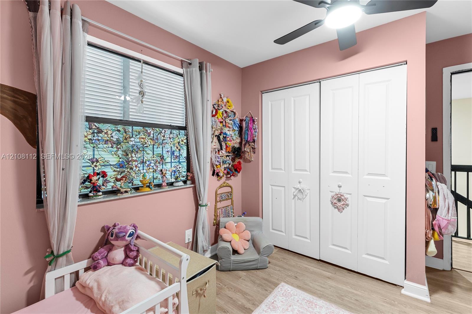 Room featuring wood-finish flooring, a double-door reach-in closet, and a ceiling fan with integrated lighting