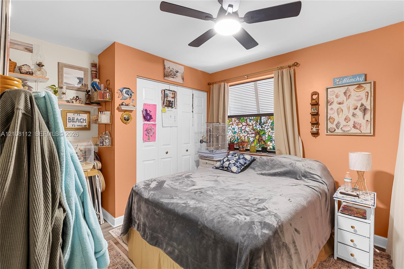 Room featuring a ceiling fan with integrated lighting, bi-fold closet doors, and decorative stained-glass window paneling