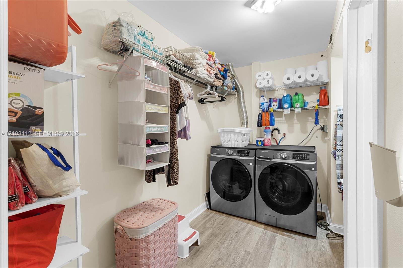 Utility space featuring wood-finish flooring, white wire wall-mounted shelving, and laundry hookups
