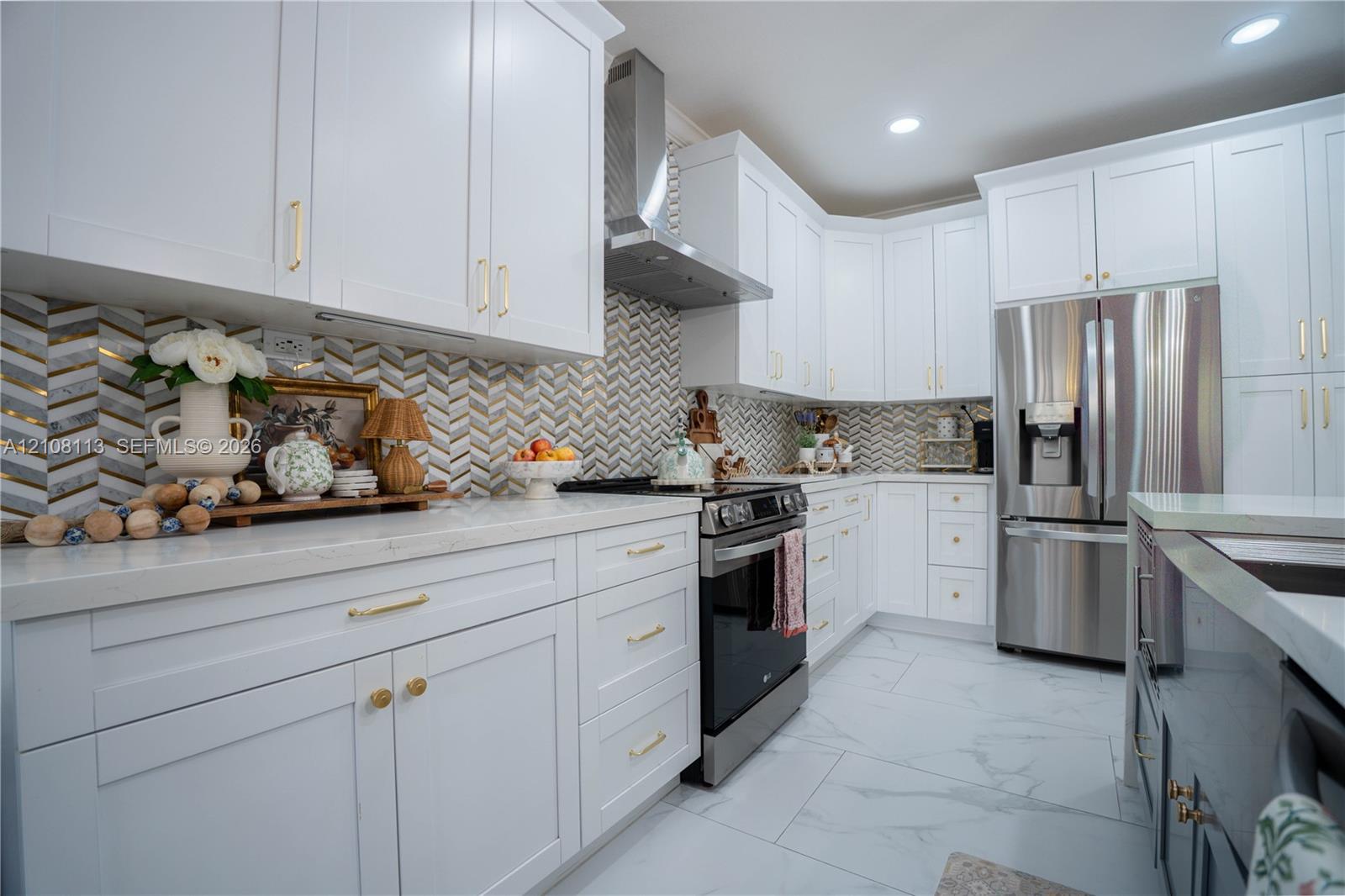 Kitchen featuring white shaker-style cabinetry, herringbone-patterned tile backsplash, stainless steel appliances, and large-format tile flooring