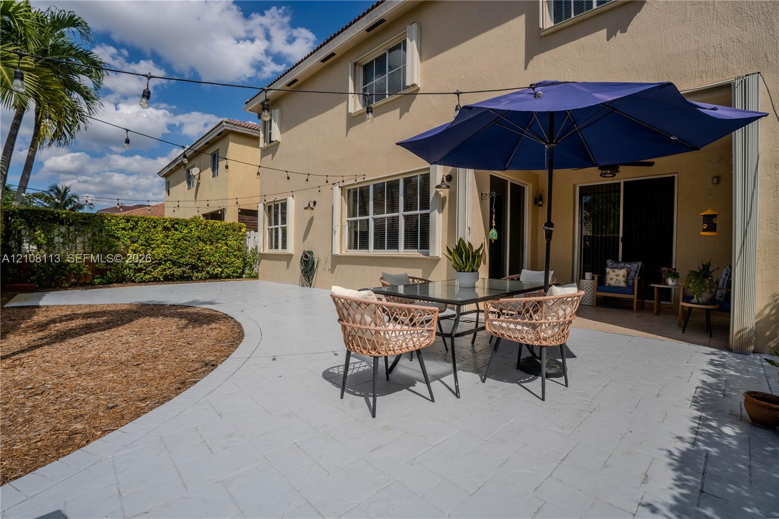 Stucco exterior featuring a paved patio, covered porch area, and integrated string lighting