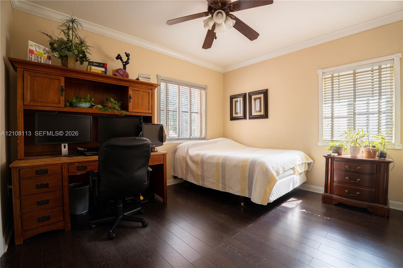 Dark wood-finish flooring, crown molding, and a central ceiling fan
