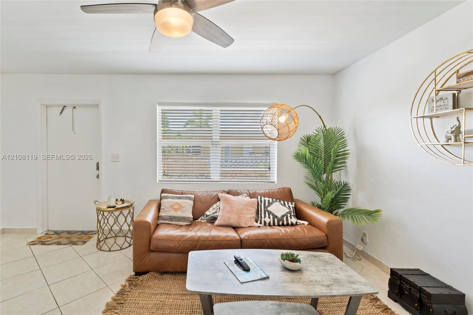 Neutral-toned ceramic tile flooring, horizontal window blinds, and a ceiling fan with an integrated light fixture