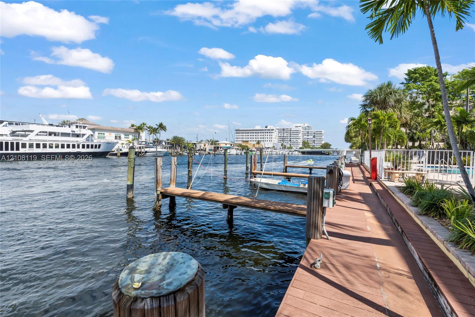 Waterfront boardwalk featuring multiple wooden boat slips, composite decking, and perimeter metal fencing