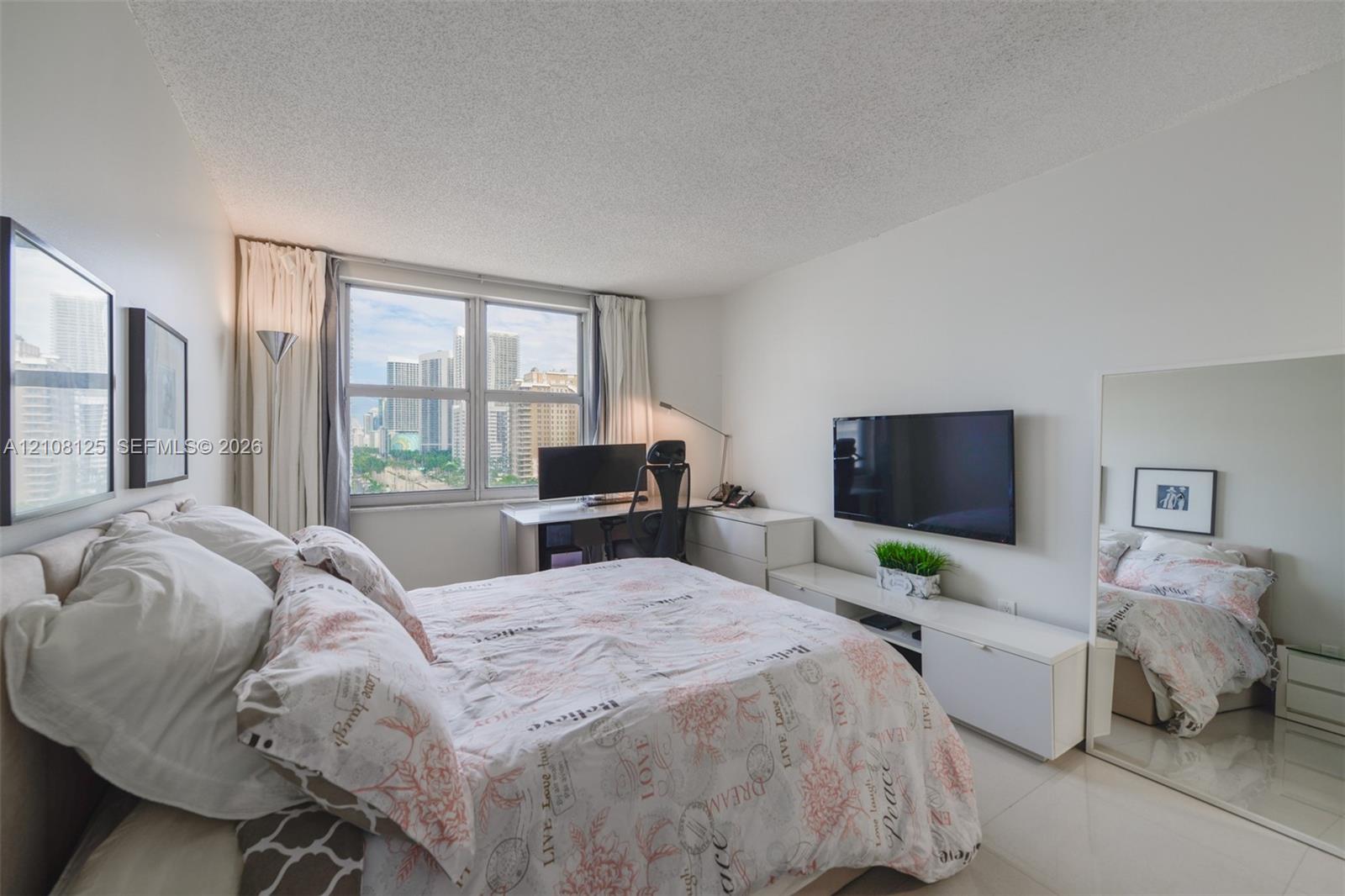 Bright room featuring large-format tile flooring, textured ceiling, expansive window, and integrated mirrored wall panel