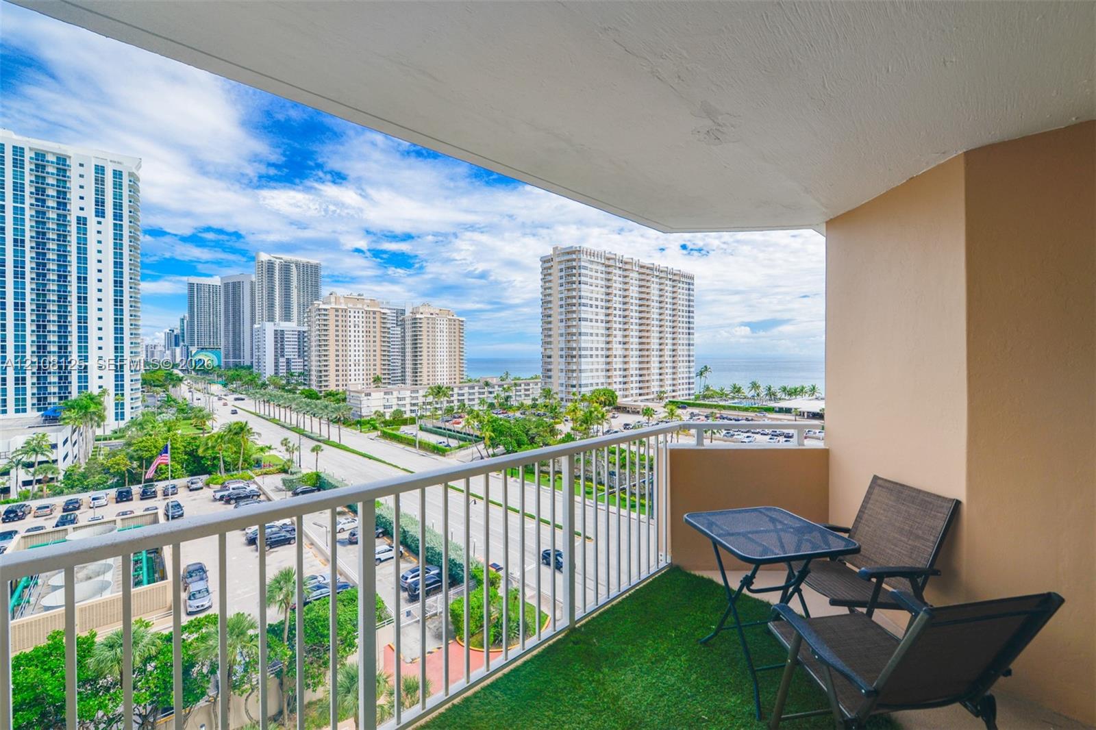 Covered balcony featuring a white metal railing and outdoor turf flooring