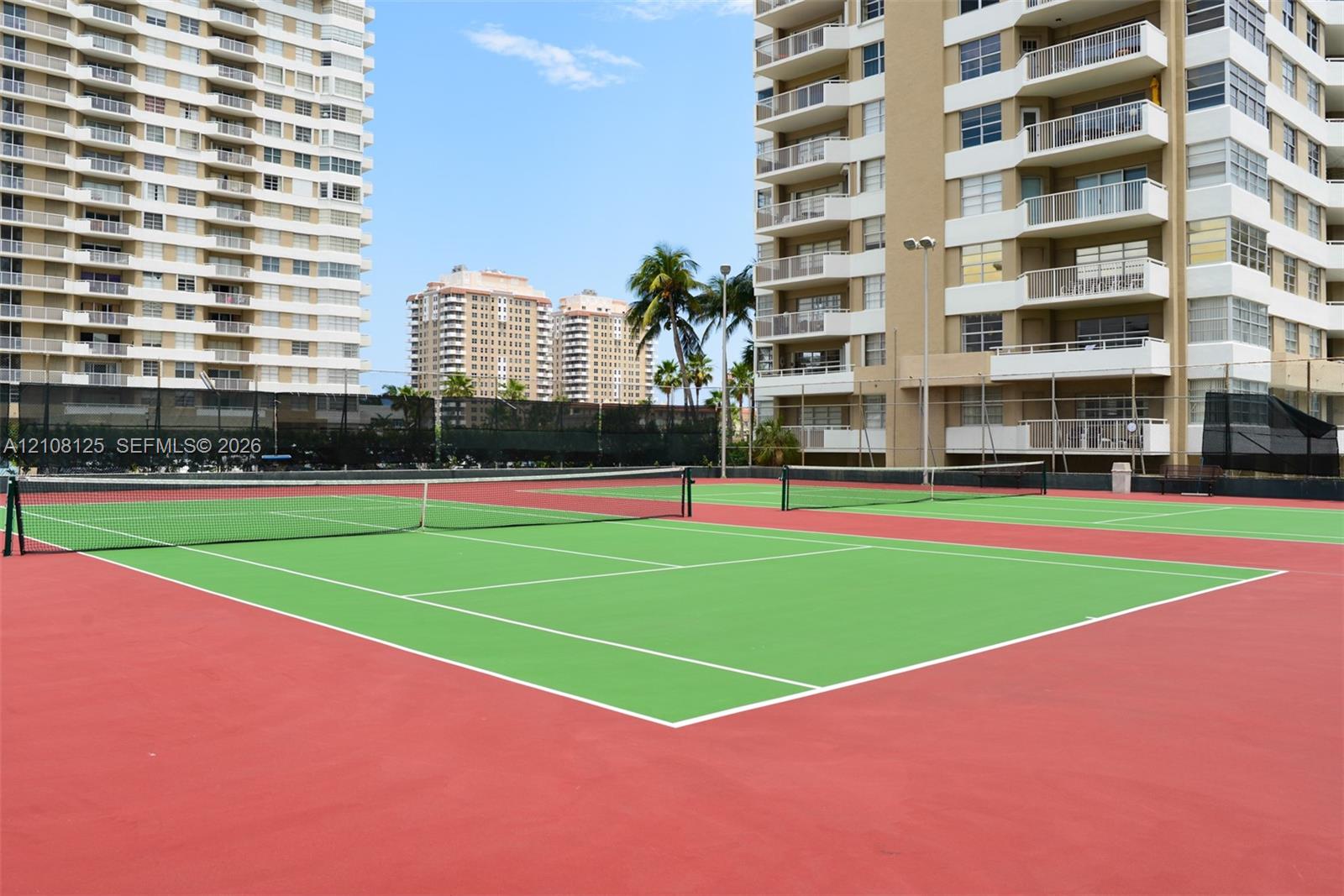Multi-court tennis facility featuring hard-surface playing areas, perimeter fencing, and high-mast lighting