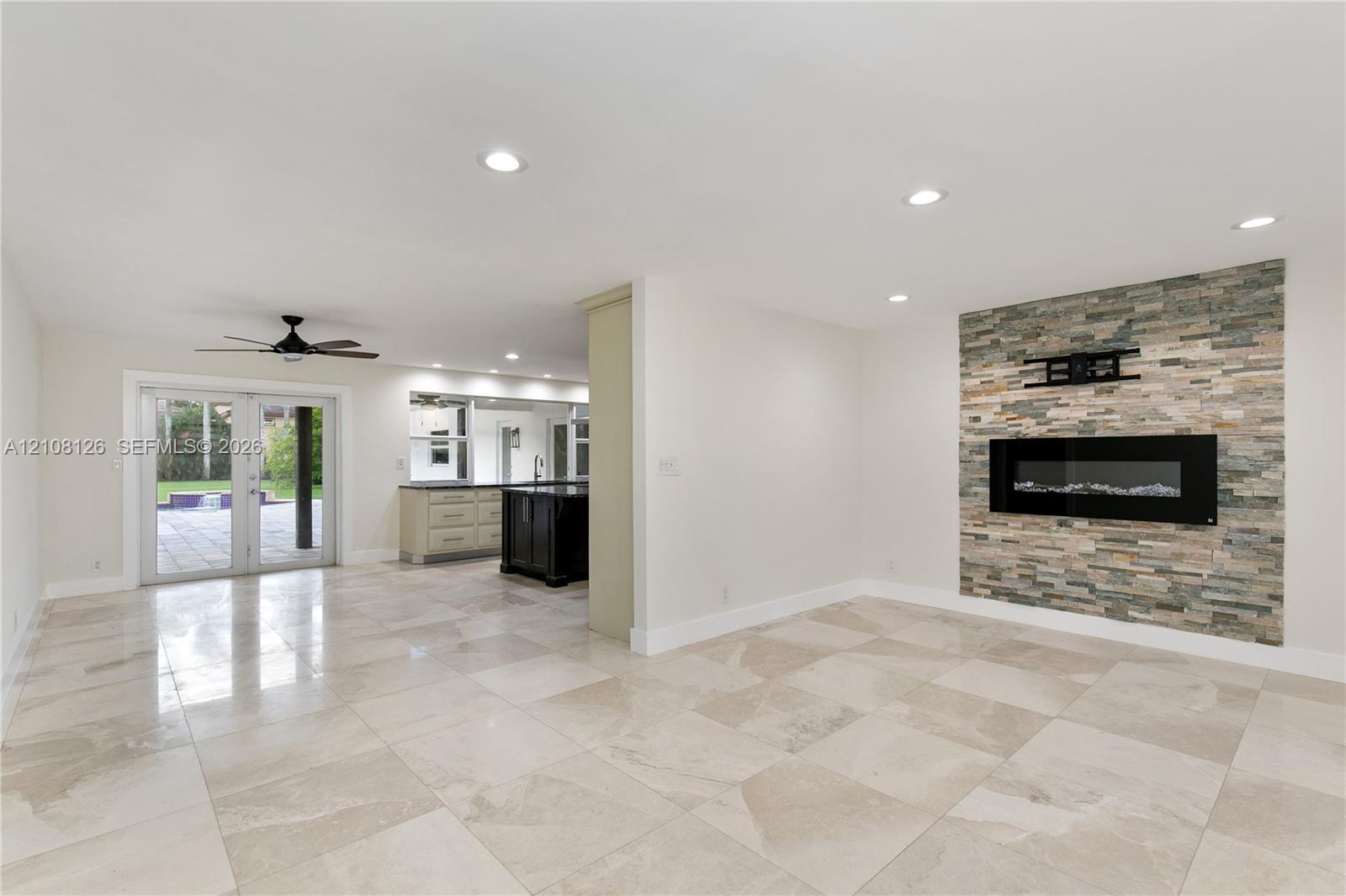 Living area featuring large-format tile flooring, recessed lighting, and a floor-to-ceiling stone-veneer accent wall with an integrated electric fireplace
