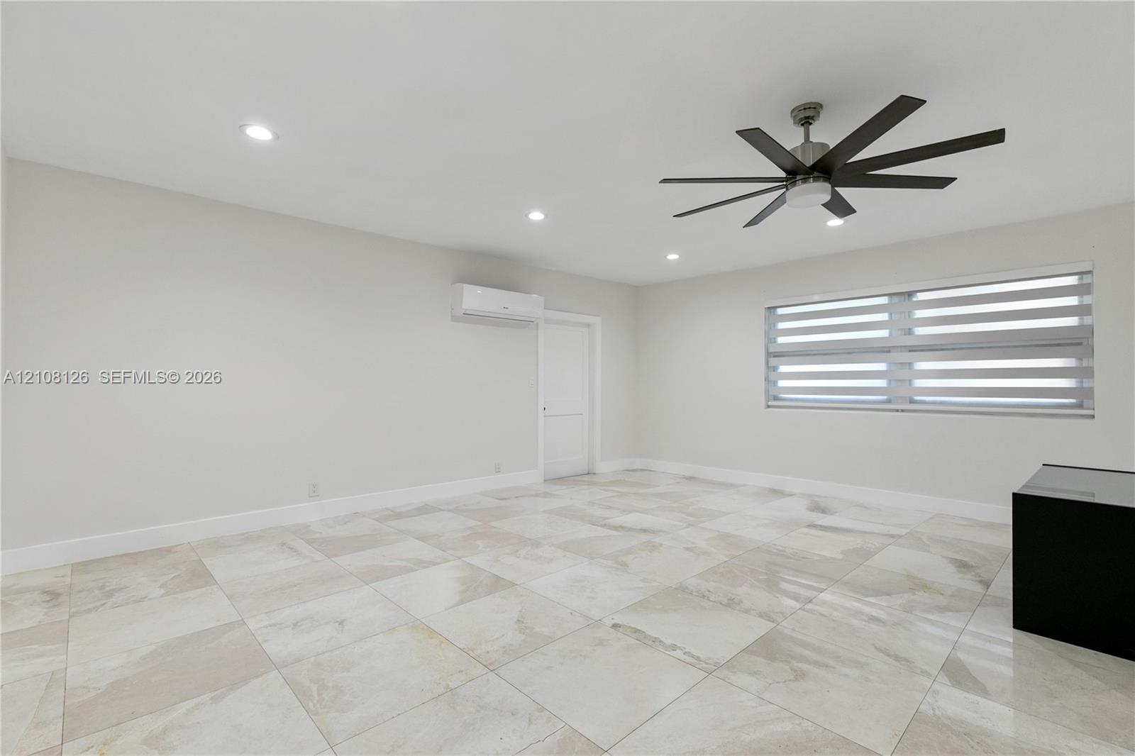 Interior space featuring large-format tile flooring, a multi-blade ceiling fan, recessed lighting, and a wall-mounted climate control unit