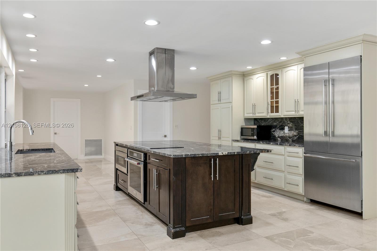Kitchen featuring a central island with a built-in oven, stone-finish countertops, stainless steel appliances, recessed ceiling lighting, and tile flooring