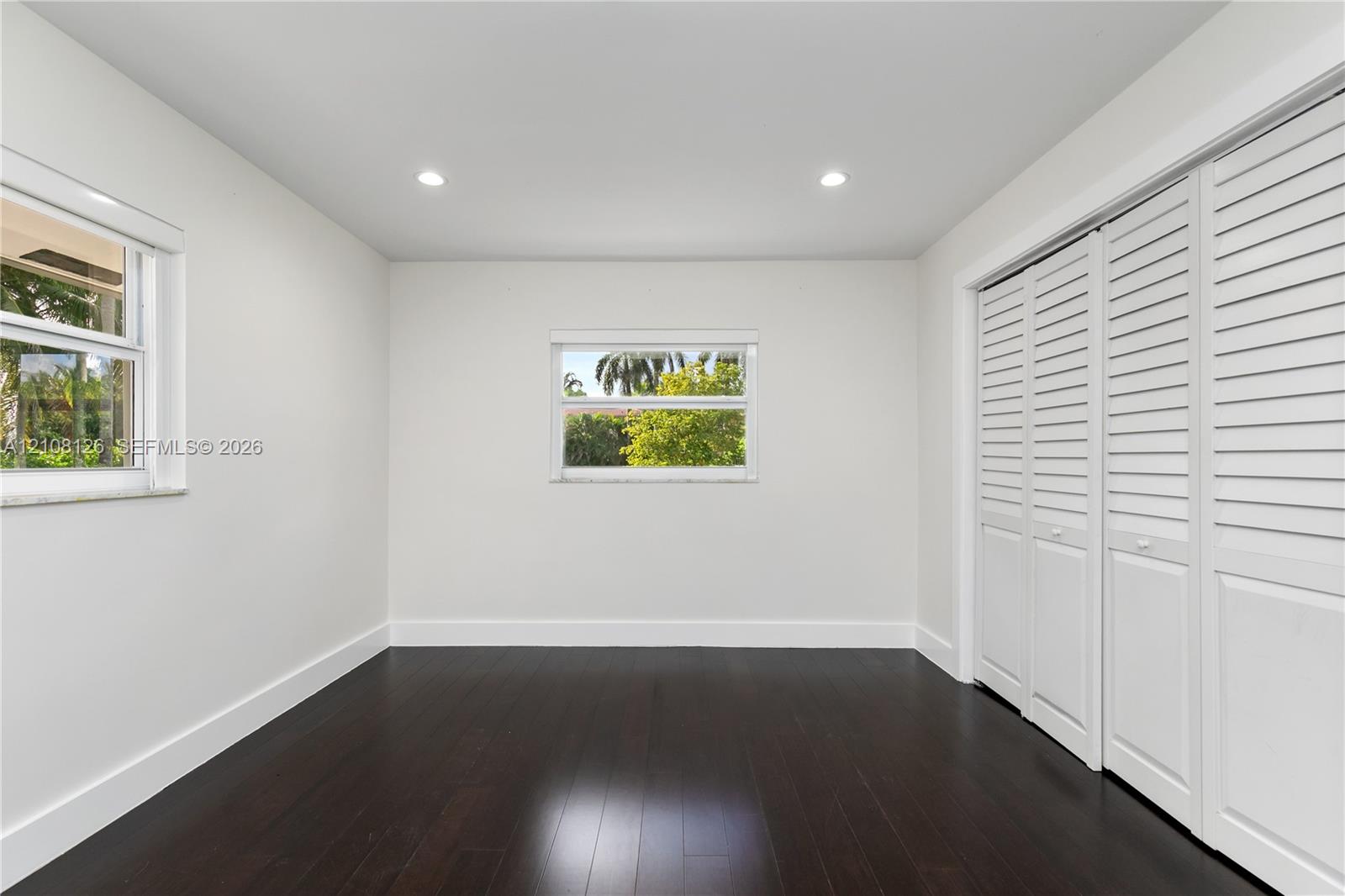 Dark wood-finish flooring, recessed lighting, and double bi-fold louvered closet doors