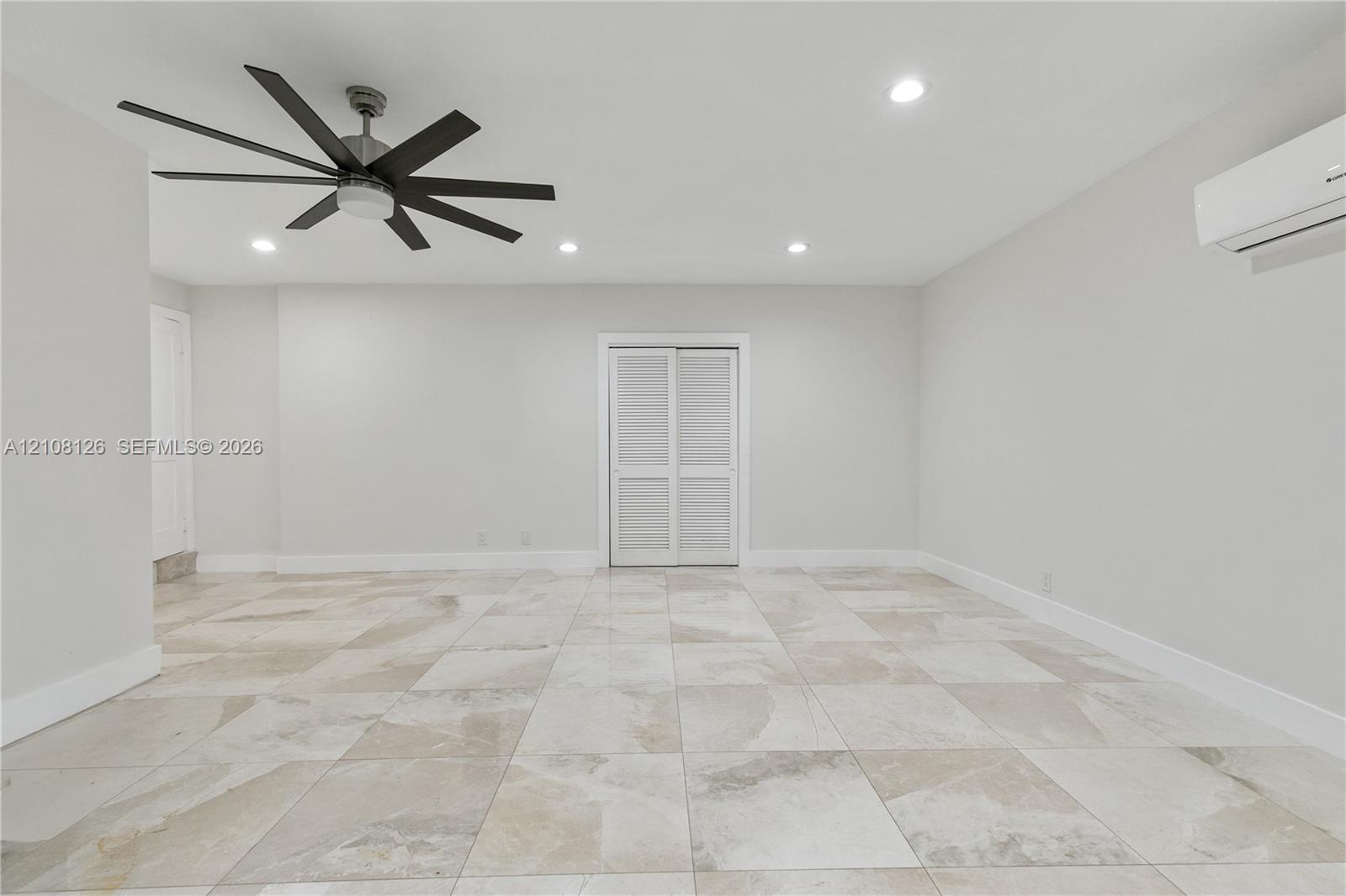 Large-format tile flooring, multi-blade ceiling fan, recessed lighting, and wall-mounted climate control unit