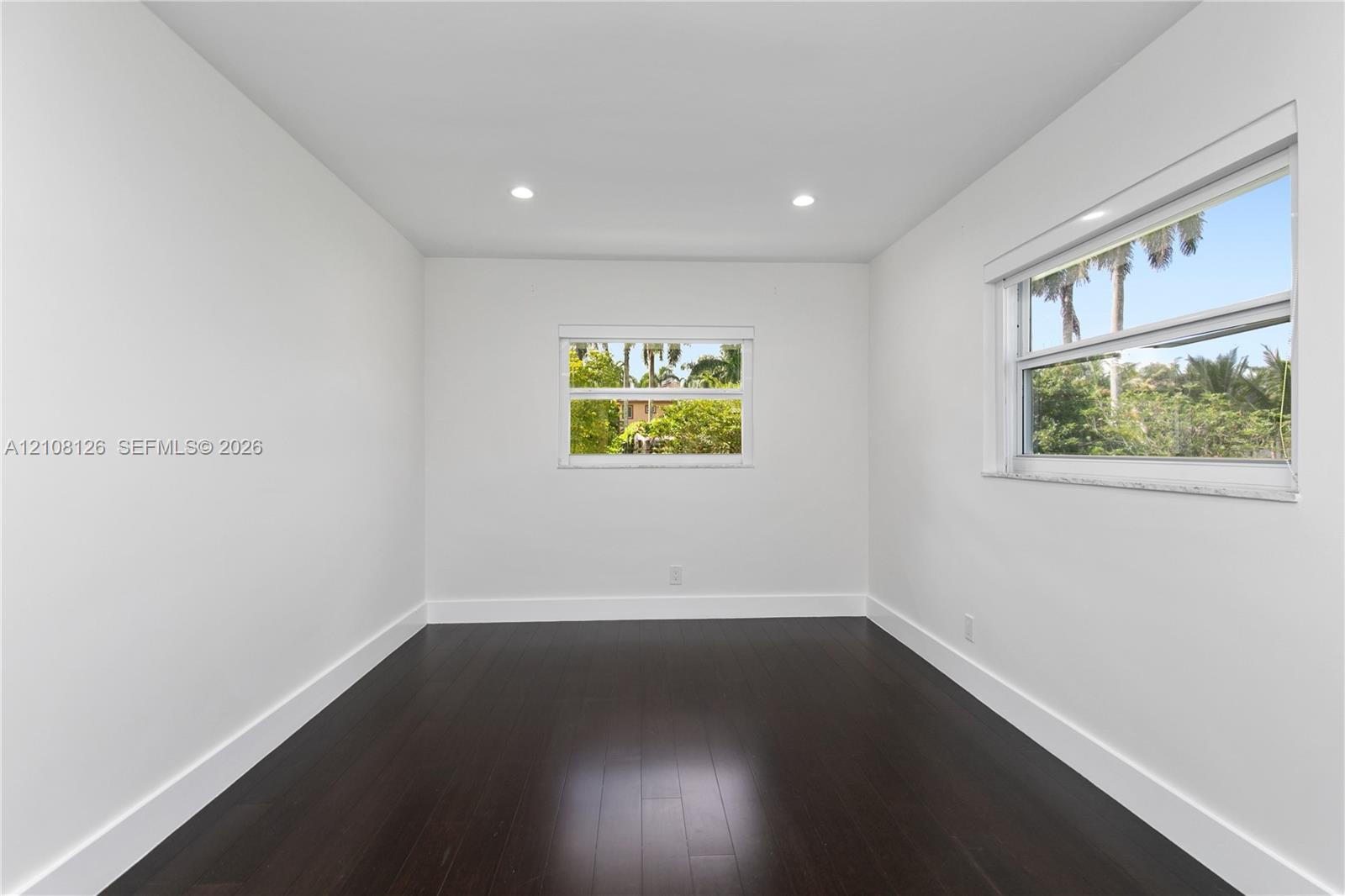 Interior space featuring dark wood-finish flooring, white walls, recessed ceiling lighting, and horizontal sliding windows