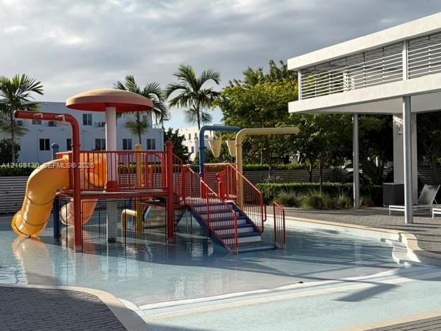 Wading pool with built-in water play structure, overhead mushroom feature, and curved slide
