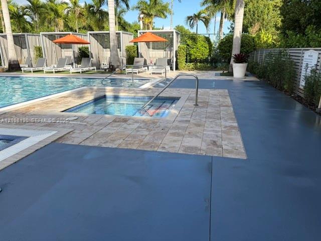 Swimming pool with integrated spa, stone-paver decking, and metal-framed poolside cabanas