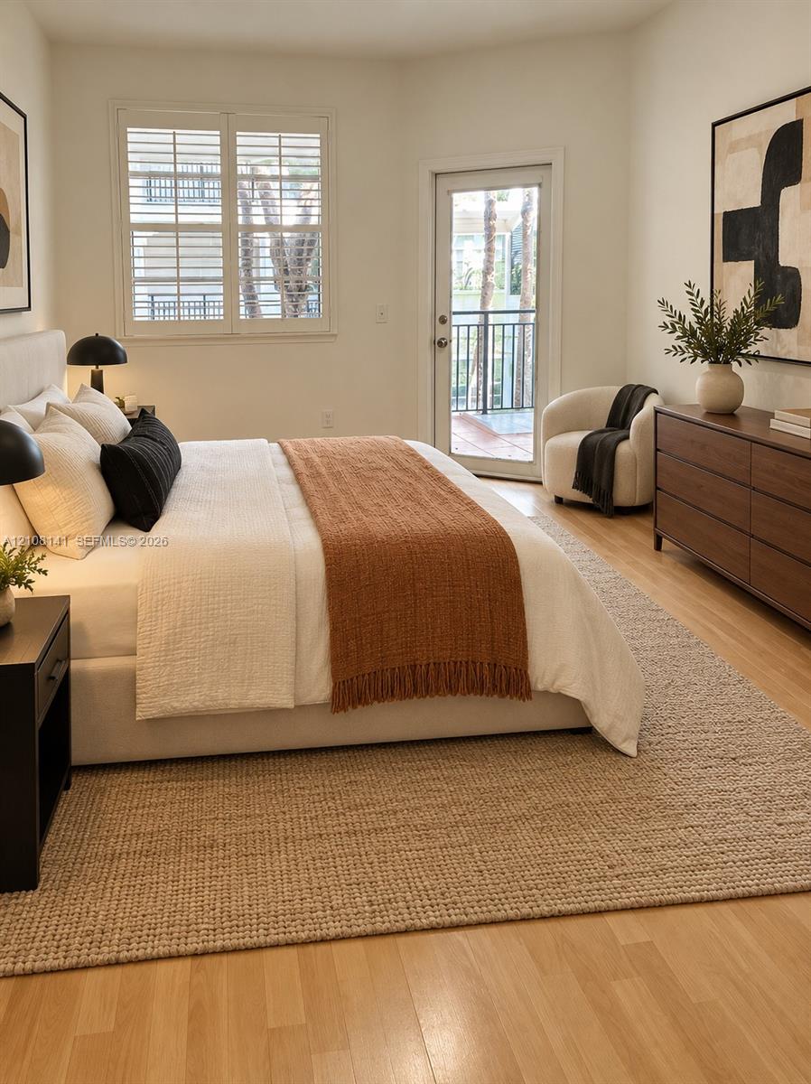 Wood-finish flooring, plantation shutters, and a private exterior door featuring a balcony with metal railing
