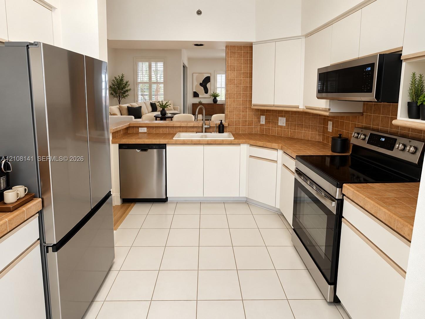 Kitchen featuring white cabinetry, tile countertops and backsplash, stainless steel appliances, and tile flooring