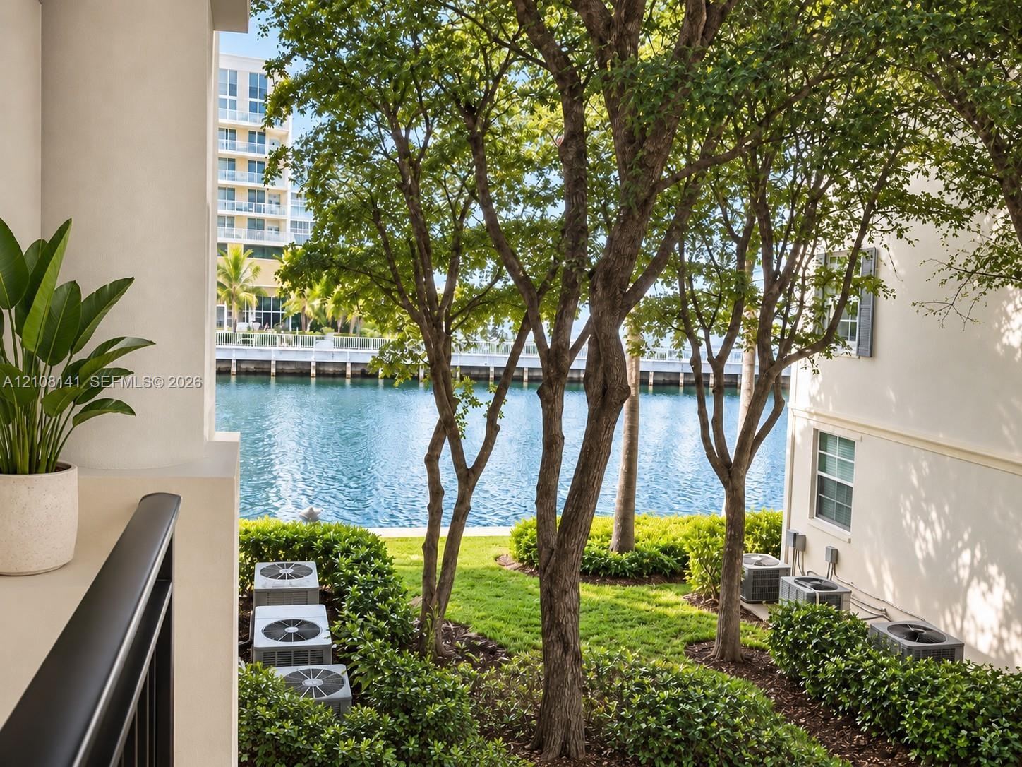 Covered terrace overlooking the intracoastal with mature trees, manicured landscaping, and a black metal railing