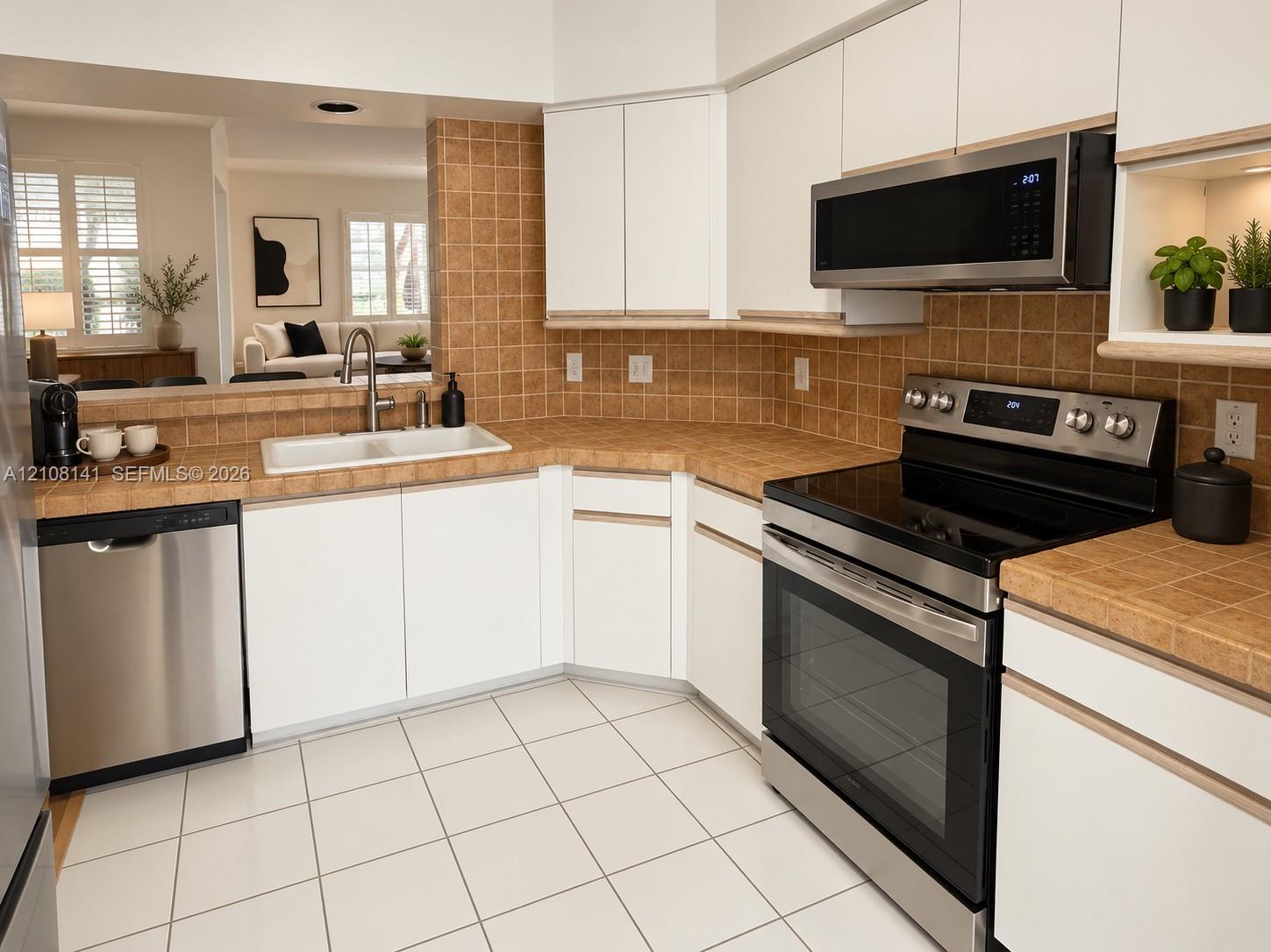 Kitchen featuring white cabinetry, stainless steel appliances, tile countertops, tile backsplash, and tile flooring