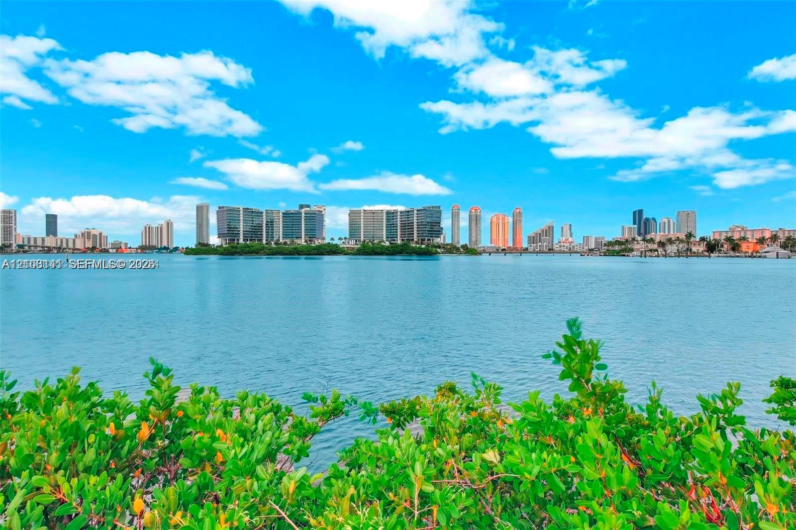 Waterfront property featuring native coastal vegetation and a panoramic urban skyline horizon