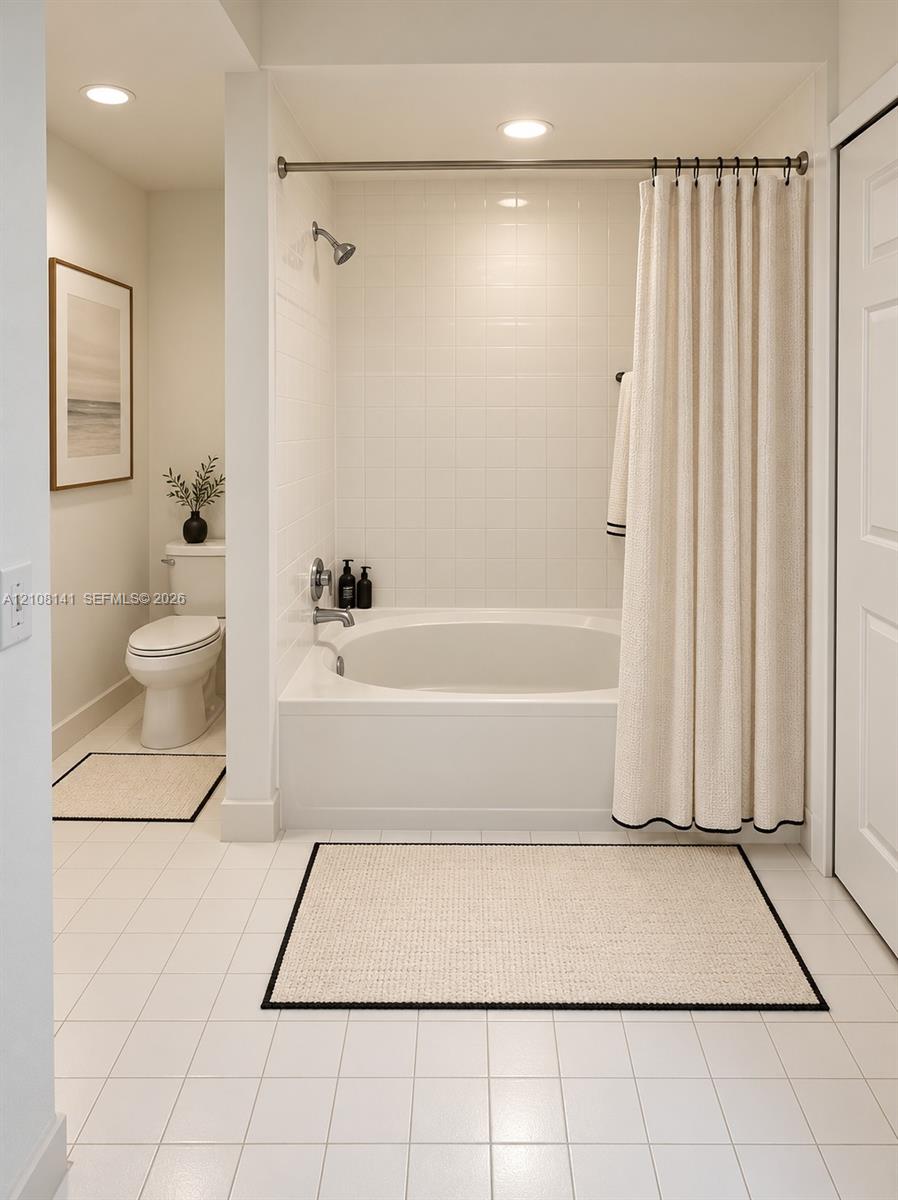 Bathroom featuring a built-in soaking tub with a tiled surround, recessed lighting, and white tile flooring