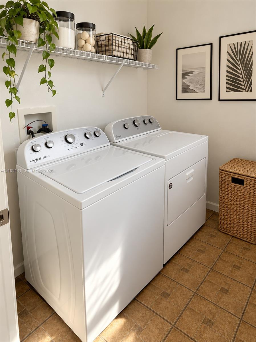 Laundry area featuring a top-loading washing machine, clothes dryer, wall-mounted wire shelving, and tiled flooring