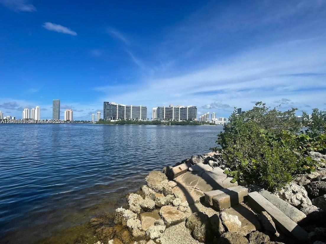 Waterfront property featuring a stone bulkhead, rocky shoreline, and native vegetation