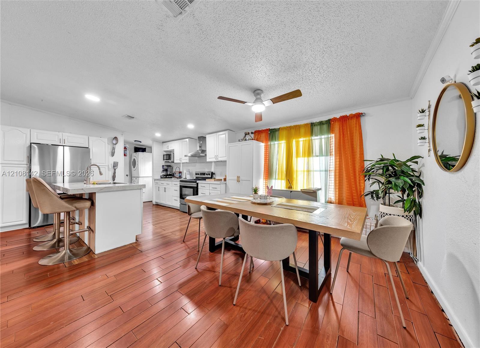 Kitchen featuring white cabinetry, an island with stone-composite countertop, stainless steel refrigerator, recessed lighting, and wood-finish flooring