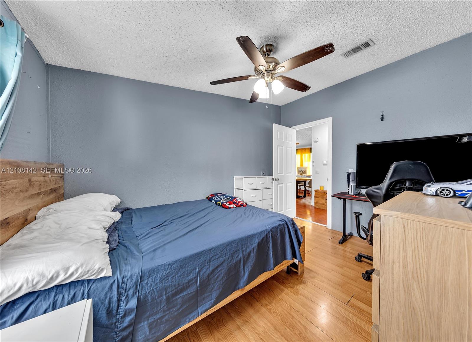 Wood-finish flooring, ceiling fan with integrated light fixture, and six-panel interior door