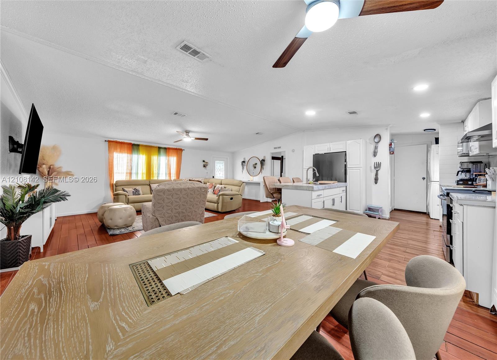Open-concept interior featuring wood-finish flooring, recessed lighting, ceiling fans, and an island kitchen with built-in cabinetry