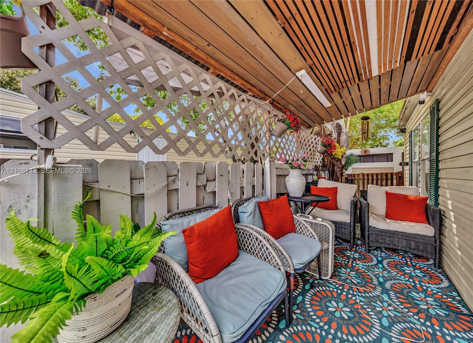 Covered outdoor patio featuring a wood-slat ceiling and decorative diamond-patterned lattice privacy screening