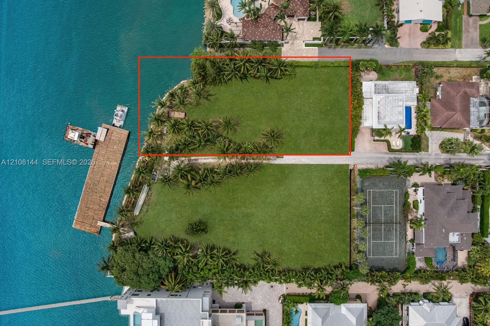 Waterfront parcel featuring direct shoreline access, expansive grass lawn, and mature perimeter landscaping