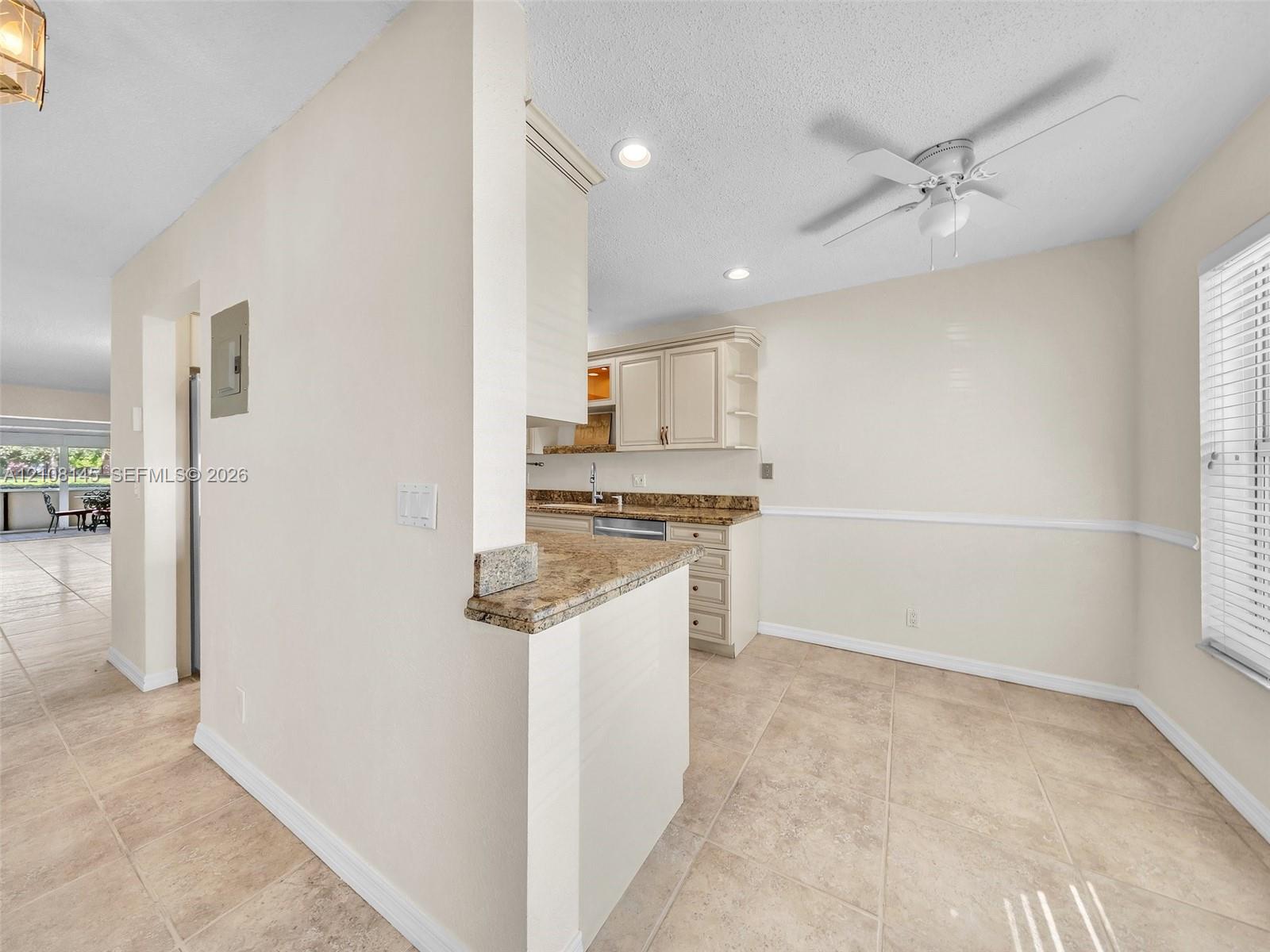 Kitchen featuring cabinetry with stone-surface countertops, tile flooring, recessed lighting, and a ceiling fan