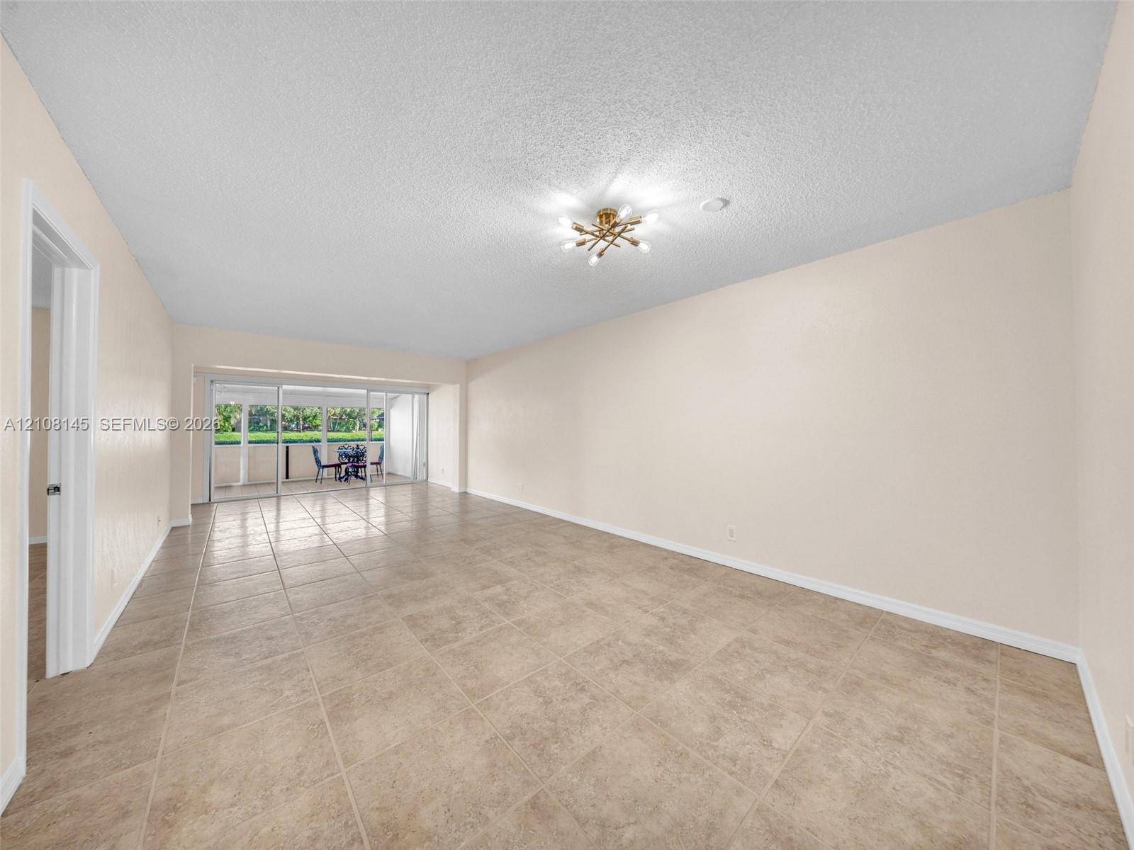 Open living space featuring large-format tile flooring, a multi-arm flush-mount light fixture, and floor-to-ceiling sliding glass doors