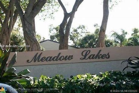 Community entrance signage featuring dimensional lettering set against a stucco monument wall with mature trees and professional landscaping