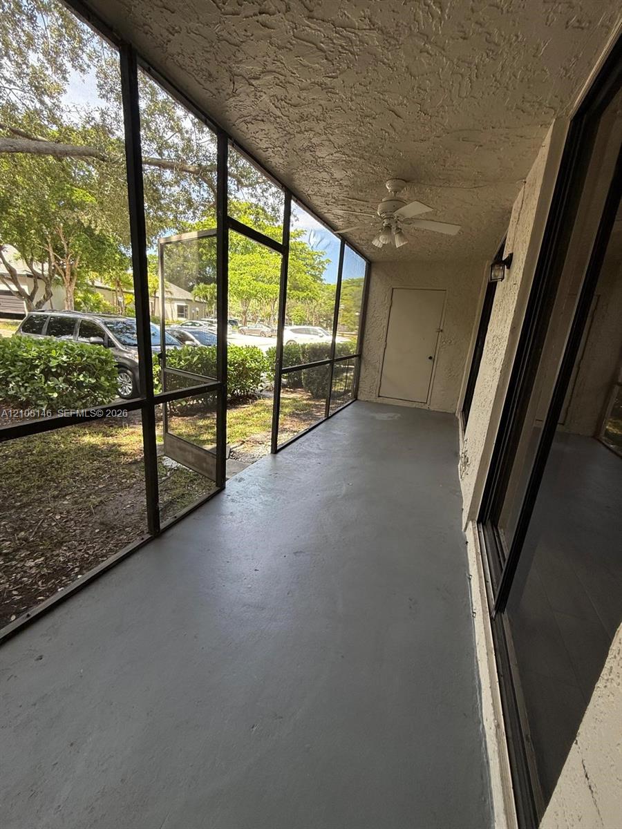 Screened-in porch featuring a painted concrete floor, a textured ceiling, a ceiling fan, and black aluminum framing