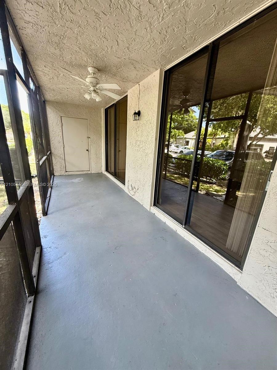 Screened-in porch featuring a ceiling fan, exterior wall-mounted light fixture, and sliding glass door access