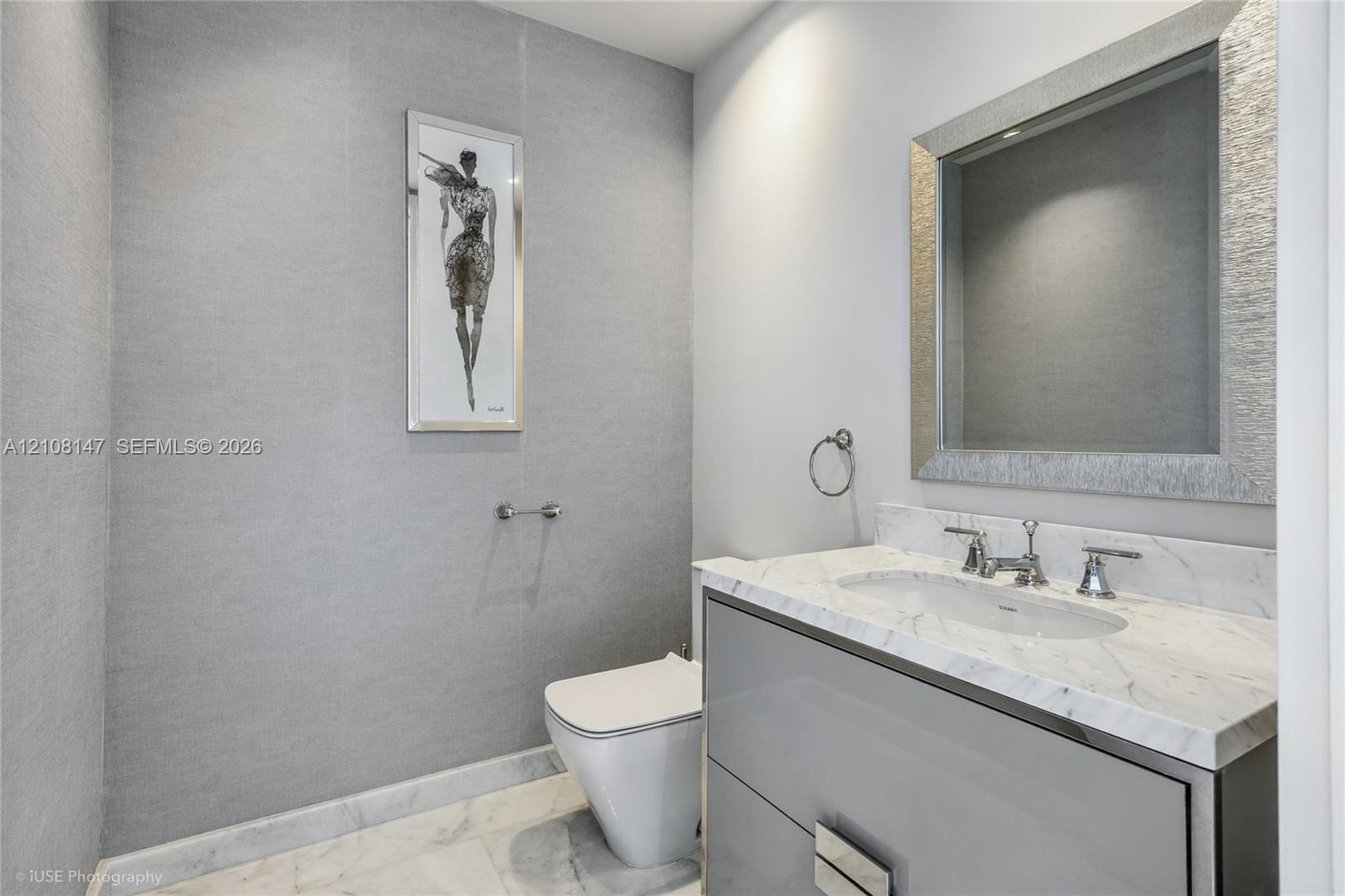 Wall-mounted vanity featuring high-gloss cabinetry, stone countertop with an integrated basin, polished chrome fixtures, and textured wall treatment