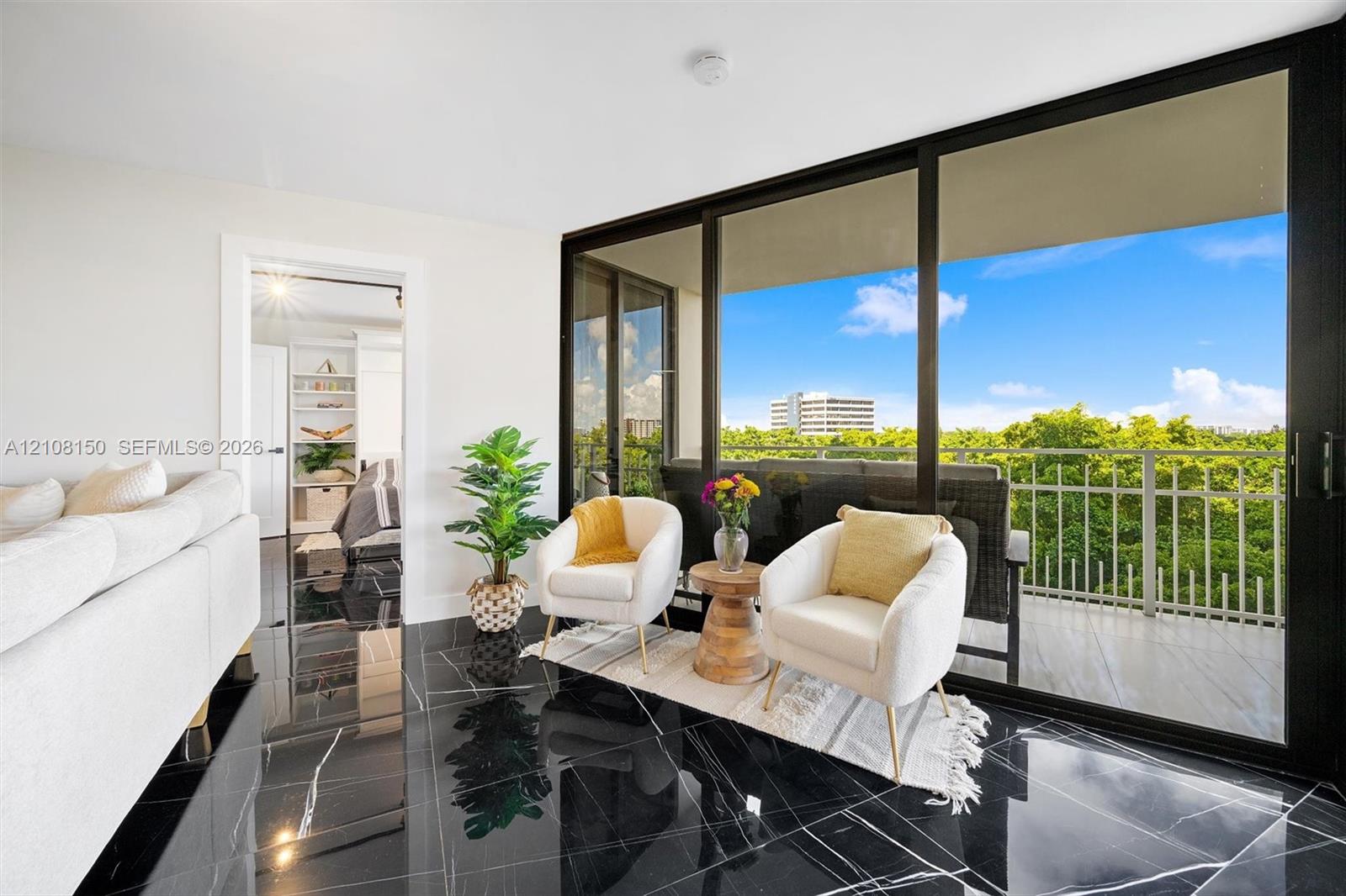Polished black flooring with white veining, expansive floor-to-ceiling sliding glass doors, and a private balcony with metal railing Polished black flooring with white veining, expansive floor-to-ceiling sliding glass doors, and a private balcony with metal railing