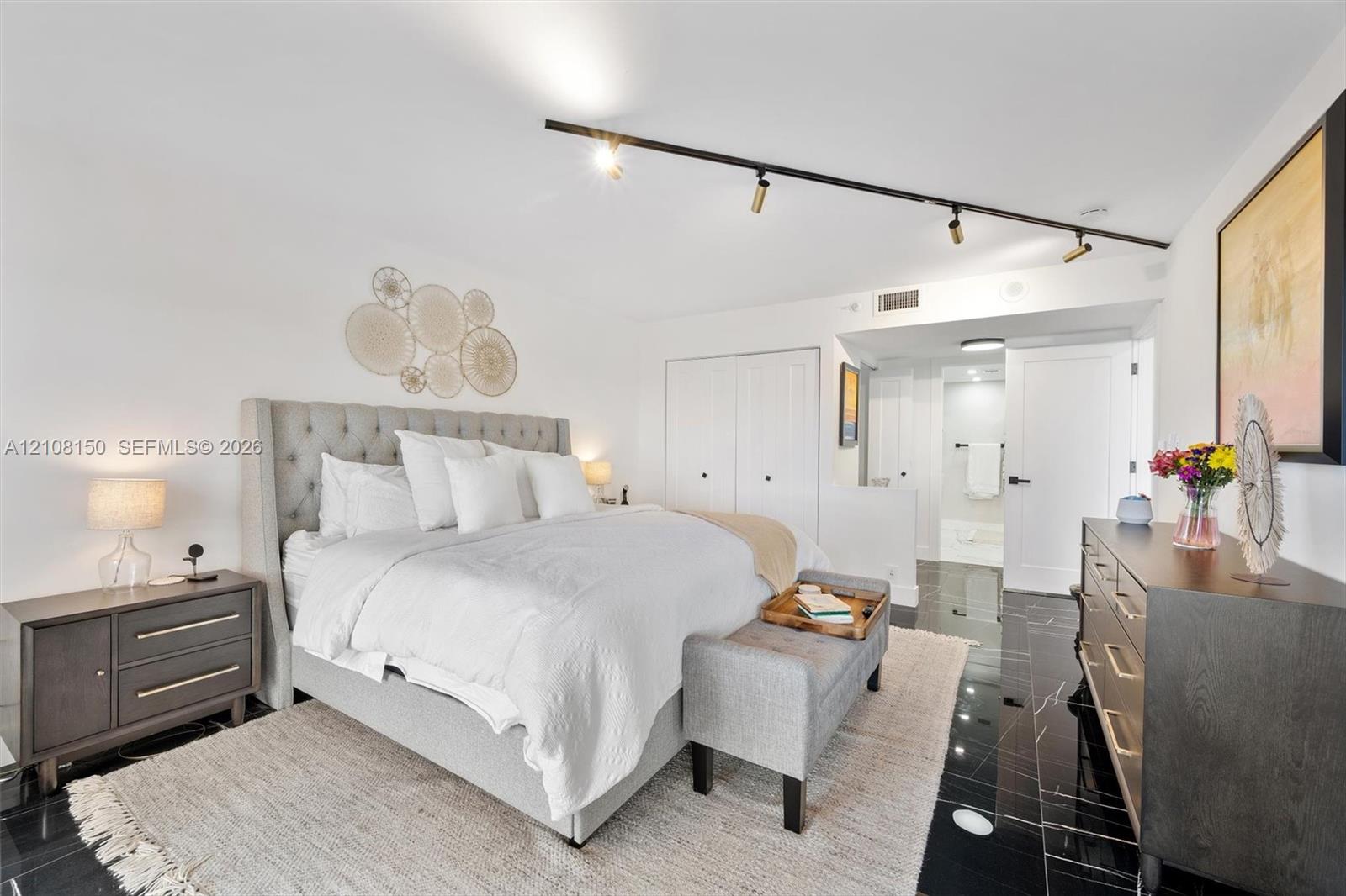 Polished black tile flooring, adjustable track lighting, and dual-door closets with matte black hardware