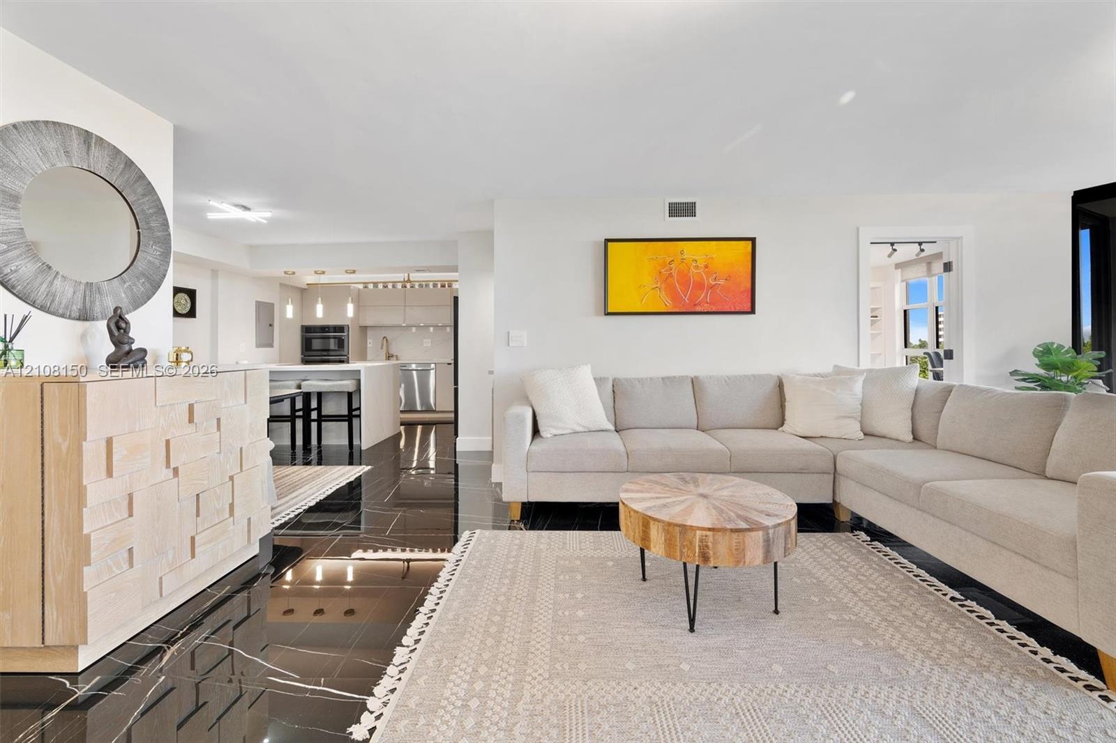 Open-concept interior featuring large-format polished dark stone flooring, recessed lighting, and kitchen cabinetry with integrated stainless steel appliances Open-concept interior featuring large-format polished dark stone flooring, recessed lighting, and kitchen cabinetry with integrated stainless steel appliances