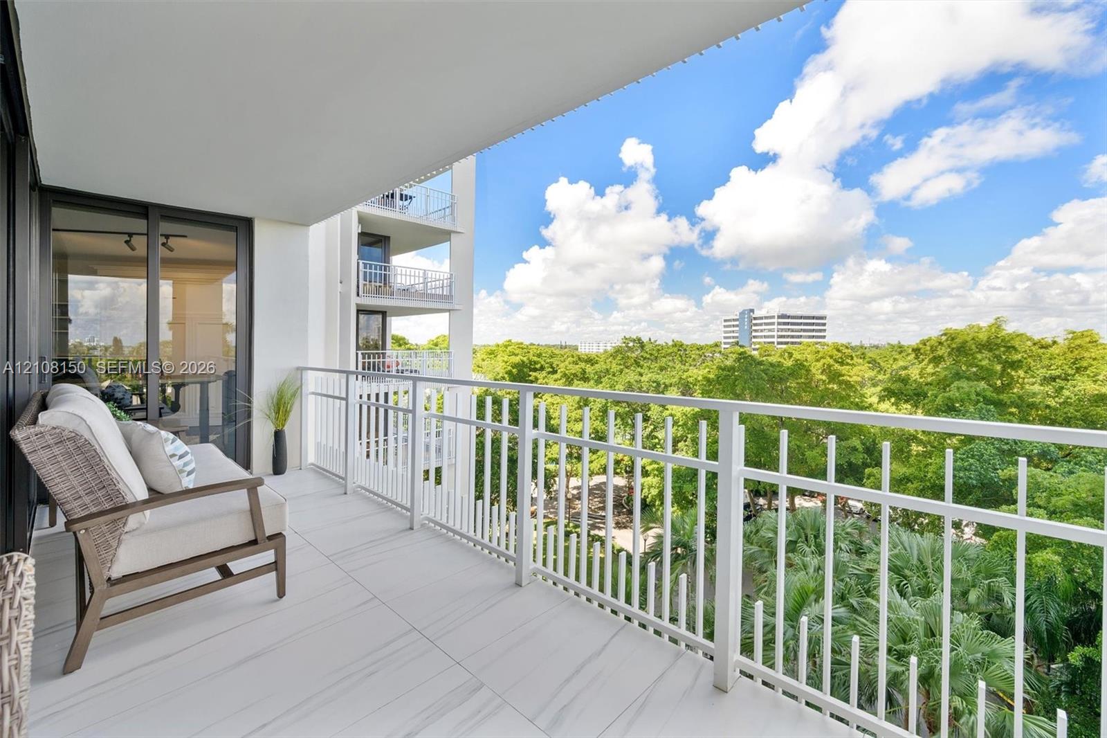 Covered balcony featuring white tile flooring, white metal railing, and sliding glass entry doors