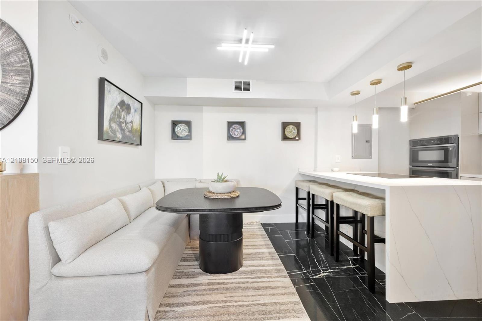 Kitchen featuring a stone-surface waterfall island, black tile flooring with white veining, built-in dual ovens, and trio of pendant lights Kitchen featuring a stone-surface waterfall island, black tile flooring with white veining, built-in dual ovens, and trio of pendant lights