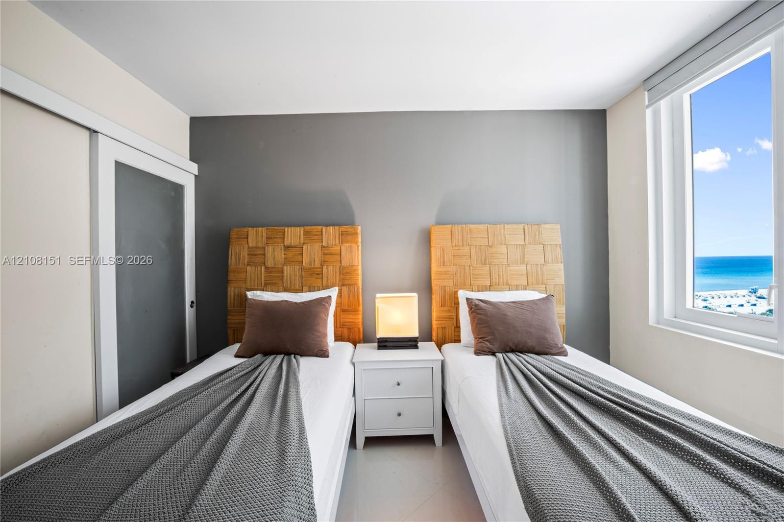 Room featuring a window with an ocean horizon, sliding door closet, and neutral-toned wall paint