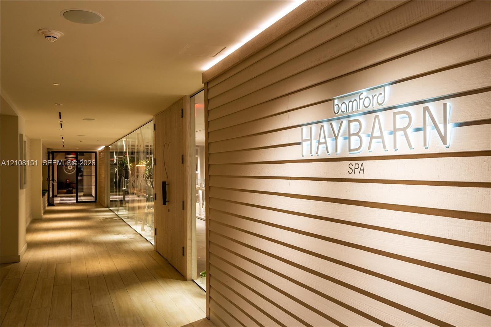 Hallway featuring horizontal wood paneling, recessed lighting, glass partition wall, and wood-finish flooring