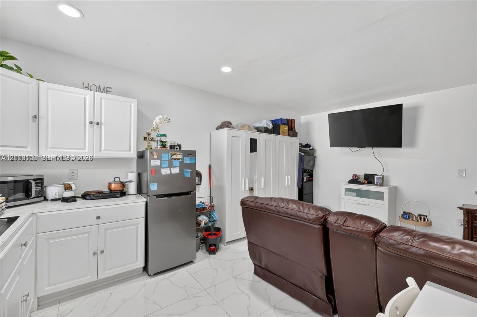 White cabinetry with silver-tone hardware, polished tile flooring, and recessed ceiling lighting