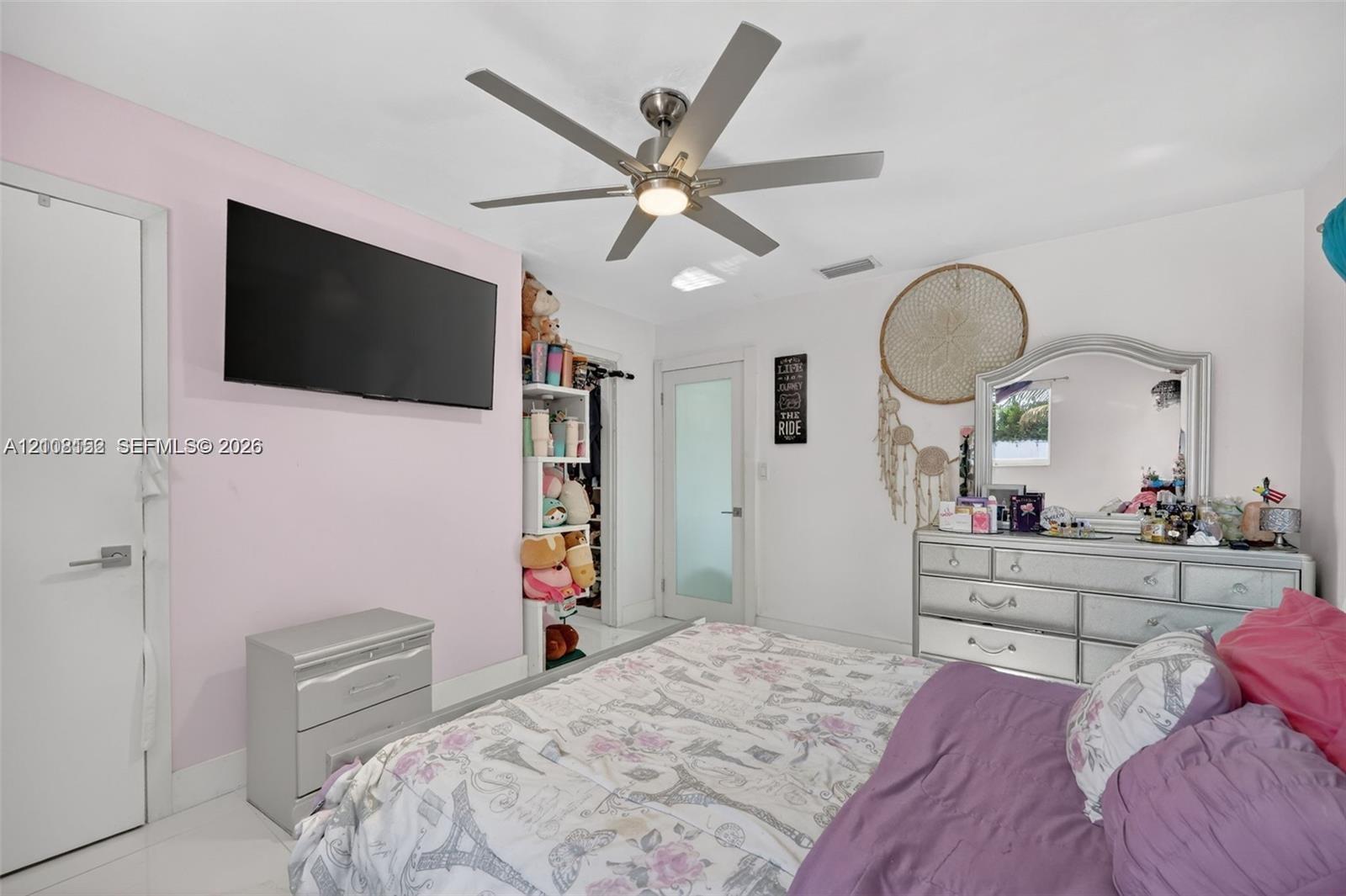 Room featuring a central ceiling fan with integrated lighting, tile flooring, and a door with a frosted glass panel