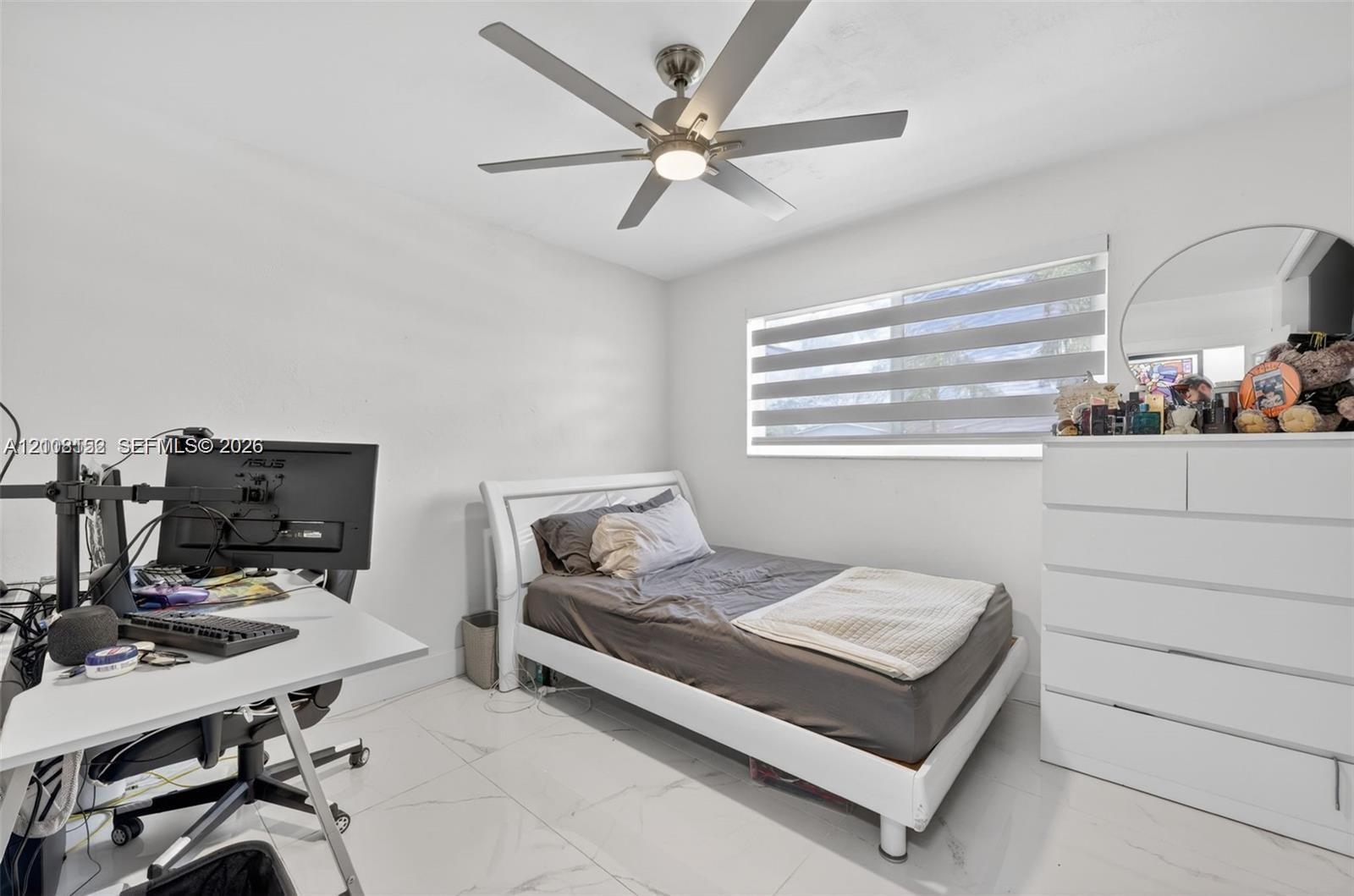 Neutral-toned room featuring large-format tile flooring, a multi-blade ceiling fan with integrated lighting, and horizontal window blinds